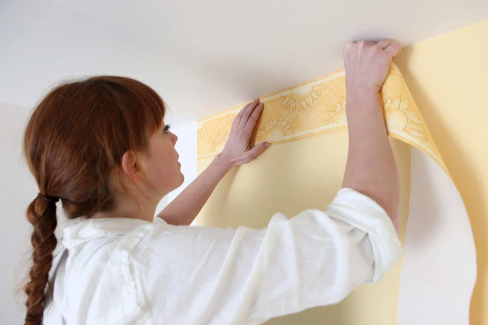 Woman hanging wallpaper on wall