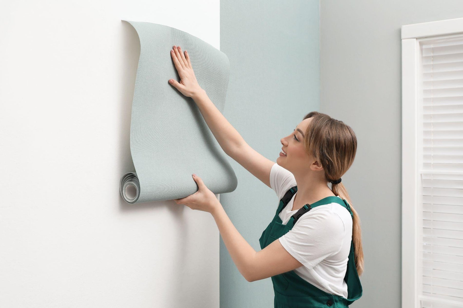 Worker hanging stylish wall paper sheet indoors