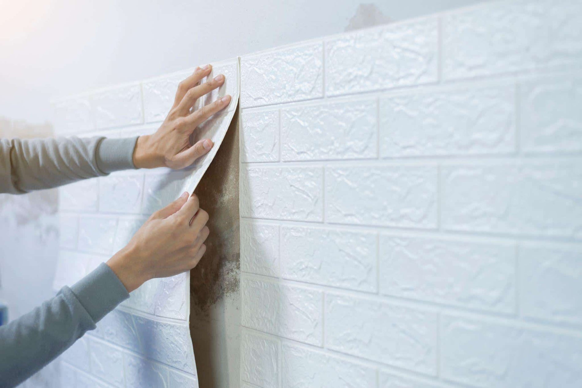 Worker hands sticking wallpaper on wall