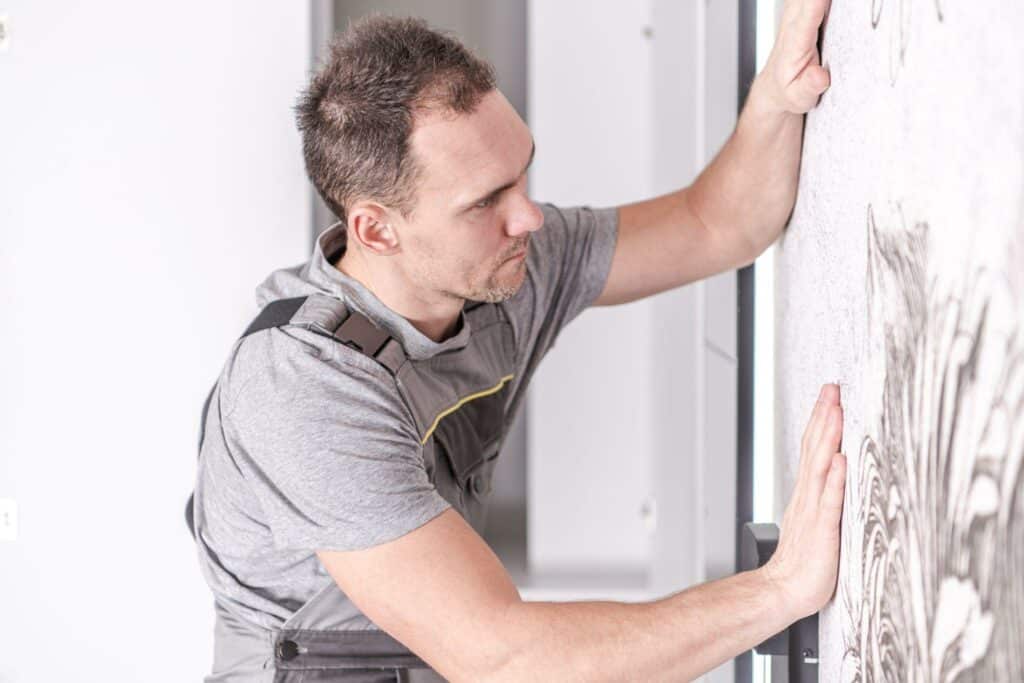 Men installing wallpaper on bedroom's wall