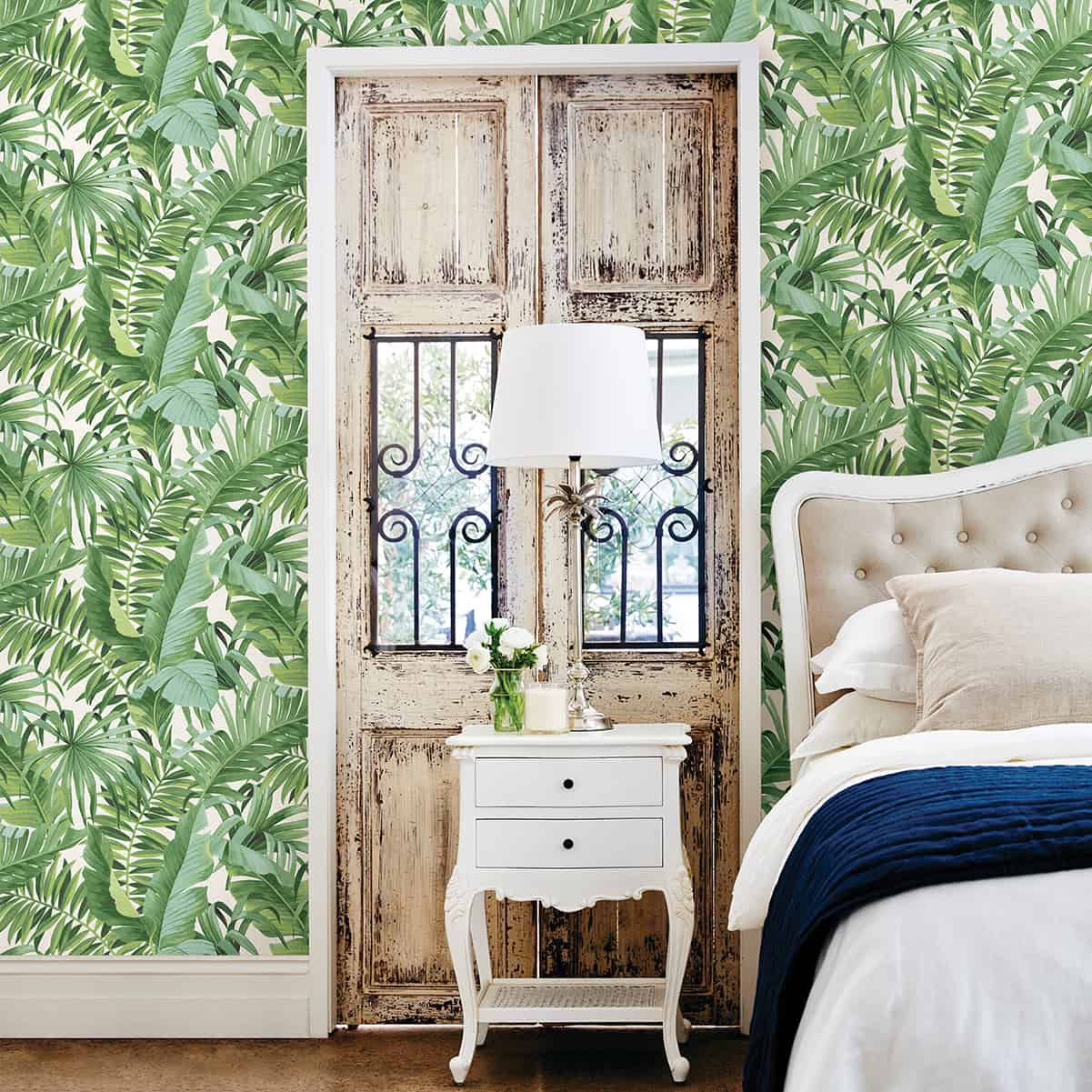 Room shot of green, tropical palm wallpaper in a bedroom.