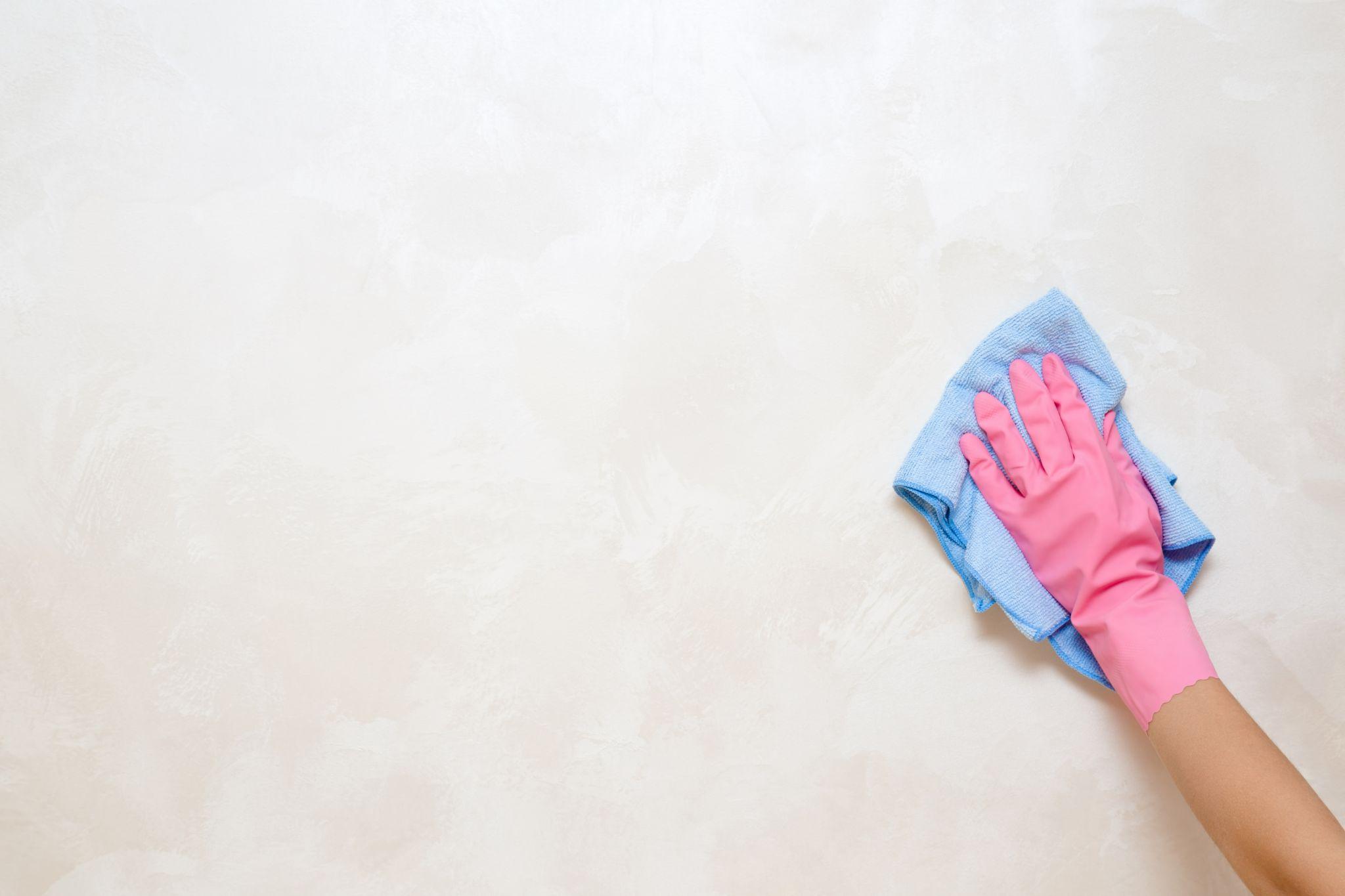 Employee hand in protective glove with rag wiping vintage wall from dust